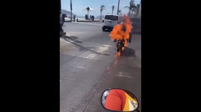 Une moto prenant feu au milieu de la route